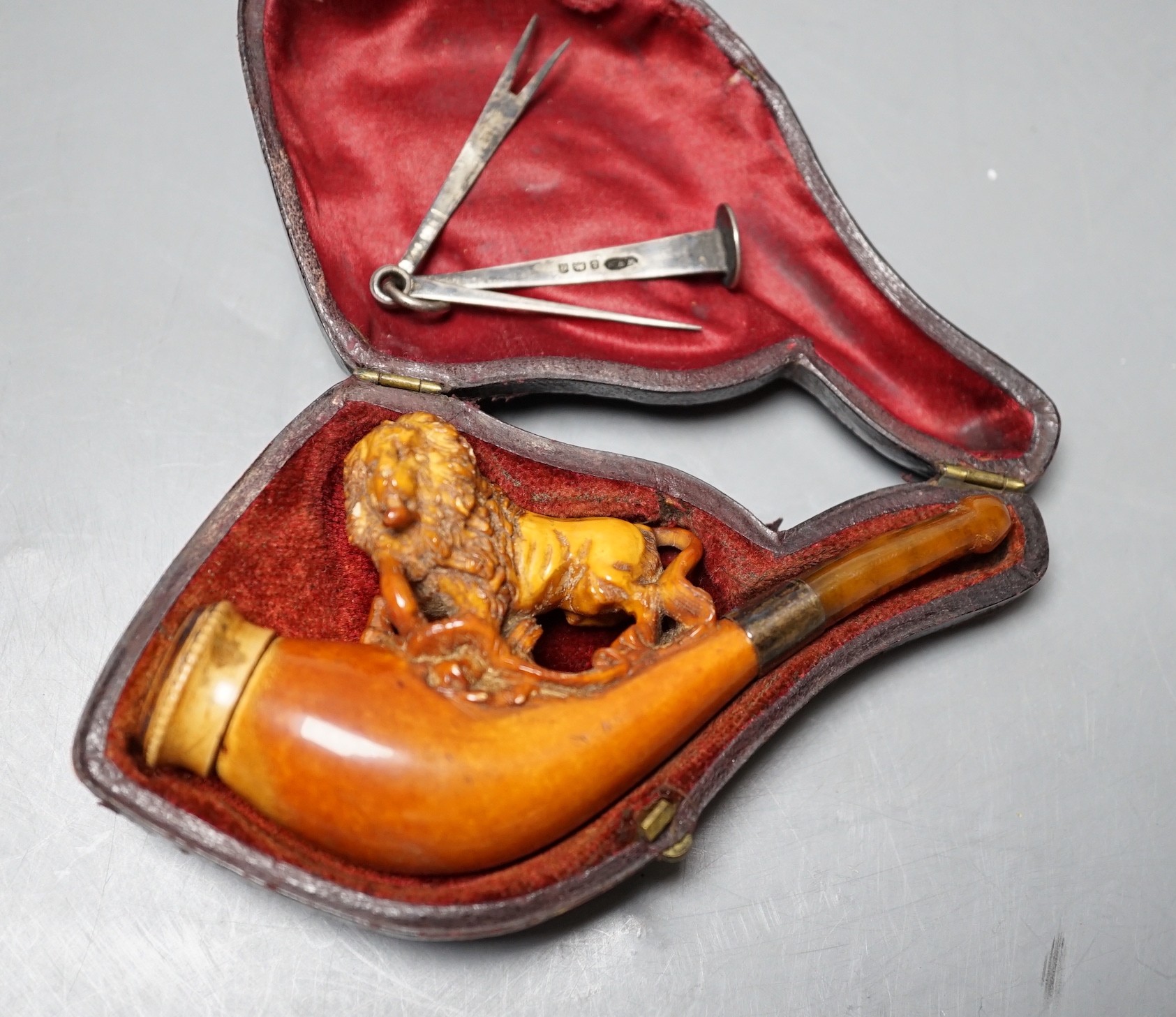 A cased Meerschaum cheroot holder with a carved wooden lion decoration with silver cleaner in fitted case, 12cm overall